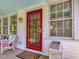 Cozy front porch with a red door, a window, and quaint seating, exuding a warm welcome at 224 E Park Dr, Raleigh, NC 27605