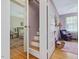 Hallway with wooden stairs and a view into a bedroom and a purple-themed room with a chair at 224 E Park Dr, Raleigh, NC 27605