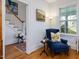 Cozy living room with a comfortable armchair, natural light, and a glimpse of the staircase at 224 E Park Dr, Raleigh, NC 27605