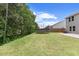 Spacious backyard featuring lush green grass, a privacy fence, mature trees, and a trampoline at 230 Purple Aster St St, Youngsville, NC 27596