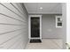 Welcoming front entrance featuring a black front door with a wreath, gray siding, and a 'hello' welcome mat at 230 Purple Aster St St, Youngsville, NC 27596
