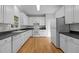 Charming kitchen featuring white cabinetry, black countertops, and hardwood floors at 2309 Clerestory Pl, Raleigh, NC 27615