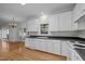 Spacious kitchen featuring white cabinetry, hardwood floors, and a black countertop at 2309 Clerestory Pl, Raleigh, NC 27615