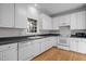Bright kitchen features white cabinetry, hardwood floors, and a black countertop at 2309 Clerestory Pl, Raleigh, NC 27615