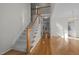 Hallway with hardwood floors, staircase, and doorway to a kitchen with white cabinets at 2309 Clerestory Pl, Raleigh, NC 27615