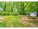 Spacious backyard showcasing mature trees, landscaping, and a charming wishing well feature at 2509 Elderwood Ln, Burlington, NC 27215