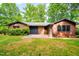 Ranch style house exterior with attached garage and surrounded by lush greenery and trees at 2509 Elderwood Ln, Burlington, NC 27215