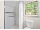 Updated bathroom with a tiled shower, white curtain, toilet, and window with exterior view at 2509 Elderwood Ln, Burlington, NC 27215