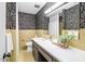 Stylish bathroom featuring floral wallpaper, cream tile wainscoting, and marble countertop vanity at 2509 Elderwood Ln, Burlington, NC 27215