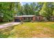 Charming brick ranch home with attached garage, mature trees, and lush front yard at 2509 Elderwood Ln, Burlington, NC 27215