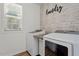 A charming laundry room with a decorative wall, window, and modern washer and dryer at 274 Tuscarora Ln, Clayton, NC 27520