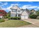 Charming two-story home features a two-car garage, blue shutters, and manicured lawn on a sunny day at 312 Grassy Point Rd, Apex, NC 27502