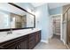 Modern bathroom featuring double sink vanity, large mirror, and walk-in shower with glass door and an adjacent walk-in closet at 3627 River Watch Ln, Franklinton, NC 27525