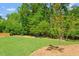 A lush backyard features an open grass area, a border of trees, and freshly laid mulch at 3932 Old Chapel Hill Rd, Durham, NC 27707