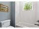 Clean white bathroom with a shower-tub, white tile surround and framed painting at 3932 Old Chapel Hill Rd, Durham, NC 27707