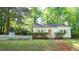 Beautiful single-story home with a brick walkway, green lawn, white picket fence, and mature trees at 409 Green St, Sanford, NC 27330