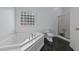 Relaxing bathroom featuring a large soaking tub, glass block window, and a separate shower stall at 411 Westhampton Dr, Burlington, NC 27215
