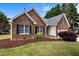 Red brick home with black shutters and manicured lawn featuring mature trees at 411 Westhampton Dr, Burlington, NC 27215