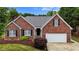 Charming brick home featuring well-maintained landscaping and attached two-car garage at 411 Westhampton Dr, Burlington, NC 27215