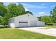 A bright white garage with multiple doors and a concrete parking pad set amid a lush green lawn on a sunny day at 4418 Carpenter Pond Rd, Durham, NC 27703