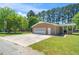 A large brick garage featuring multiple doors and a spacious concrete pad for ample parking and outdoor activities at 4418 Carpenter Pond Rd, Durham, NC 27703