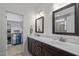 Well-lit bathroom featuring double sinks, wooden cabinets, large mirrors, and a walk-in closet at 47 Scarlet Bell Dr, Youngsville, NC 27596