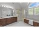 Bright bathroom featuring a dual sink vanity, walk-in shower, and soaking tub with large windows at 5 Bobby Parker Pl, Durham, NC 27703