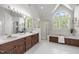 Bright bathroom featuring a dual sink vanity, walk-in shower, and soaking tub with large windows at 5 Bobby Parker Pl, Durham, NC 27703