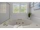 Close up of soaking tub with a view of the large shuttered windows and greenery beyond at 5 Bobby Parker Pl, Durham, NC 27703