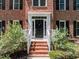 A stately brick home with a classic black front door, white trim, and manicured landscaping at 5 Bobby Parker Pl, Durham, NC 27703