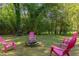 Lush backyard featuring bright pink Adirondack chairs gathered around a modern fire pit, perfect for outdoor gatherings at 508 E Trinity Ave, Durham, NC 27701