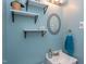 Bathroom with a blue wall and shelves. Features a sink, mirror, and wall decor at 508 E Trinity Ave, Durham, NC 27701
