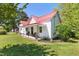 Charming home featuring a red metal roof, inviting front porch with seating, and well-manicured green lawn at 5423 Nc-39, Selma, NC 27576
