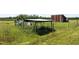 Fenced garden area with an outbuilding set amidst a lush, grassy field, blending functionality with natural beauty at 5423 Nc-39, Selma, NC 27576