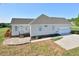Rear exterior with a stone patio, deck, and three-car garage with paved driveway at 55 Derwin Dr, Timberlake, NC 27583
