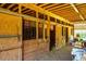 Wood paneled horse stalls inside of a rustic barn with a lawn mower in the back at 5916&5918 Laws Farm Rd, Rougemont, NC 27572