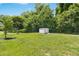 Well-maintained backyard with healthy green grass, mature trees and a storage building, offering a serene outdoor space at 624 Wait Ave, Wake Forest, NC 27587