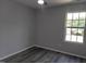 Bright bedroom featuring gray walls, wood floors, ceiling fan, and large window at 7 Mint Hill Ct, Durham, NC 27703