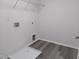 Neutral laundry area with gray wood-look flooring, white walls, shelving, and utility connections at 7 Mint Hill Ct, Durham, NC 27703