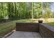 Lush backyard with brick retaining wall, mature trees, and a wood fence; perfect for outdoor enjoyment at 7200 Rabbit Run, Wake Forest, NC 27587