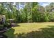 Expansive backyard featuring a spacious lawn, mature trees, and a deck with an umbrella and grill at 7200 Rabbit Run, Wake Forest, NC 27587