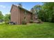 Expansive backyard featuring a brick exterior, wooden deck, lush green lawn, and mature trees at 804 Warwick Ct, Burlington, NC 27215