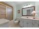 Bright bathroom with a single sink vanity, framed mirror, and a shower-tub with sliding glass doors at 804 Warwick Ct, Burlington, NC 27215