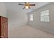 Carpeted bedroom featuring a ceiling fan with lights, two windows, and light neutral walls at 804 Warwick Ct, Burlington, NC 27215