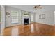 Spacious living room with hardwood floors, a decorative fireplace, a ceiling fan, and large windows at 804 Warwick Ct, Burlington, NC 27215