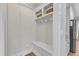 Bright mudroom with white bench, coat hooks, overhead storage, and paneled wall detail near kitchen at 1012 Wandering Way, Rolesville, NC 27571