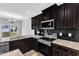 Close up of a kitchen featuring stainless steel appliances, dark cabinetry, and stylish backsplash and granite countertops at 1013 Fieldmere Pl, Wendell, NC 27591