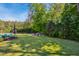 Spacious backyard with manicured lawn, mature trees, and a cozy fire pit area, perfect for outdoor activities at 106 Mesquite Dr, Durham, NC 27703