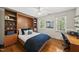 Bedroom with hardwood floors, a Murphy bed with shelving, and two windows with blinds at 108 Westport Dr, Cary, NC 27511