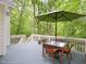 A cozy outdoor dining set with an umbrella on a wood deck surrounded by trees at 110 Blackford Ct, Durham, NC 27712